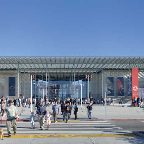 The front entrance of the California Academy of Sciences under a clear, blue sky