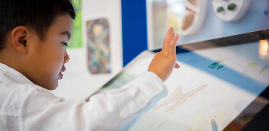 A young visitor explores the Macro Color magnifier on exhibit at the Academy