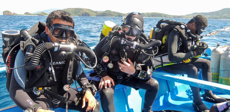 A trio of Academy scientists on a boat in scuba gear, ready to dive Palau.