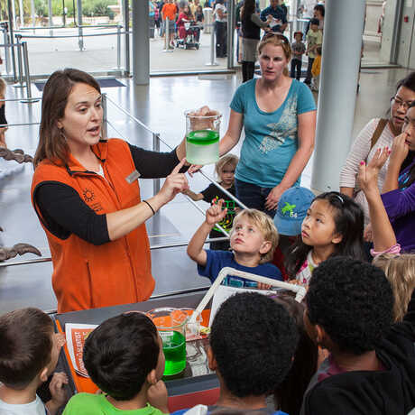 A public program presenter with a group of fascinated youngsters