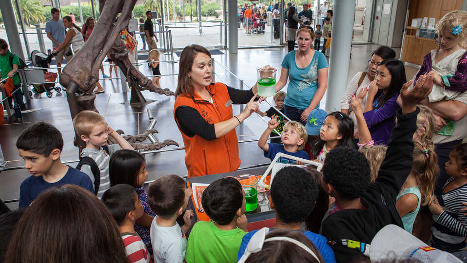 Students gathered around a docent giving a demonstration on ocean acidification